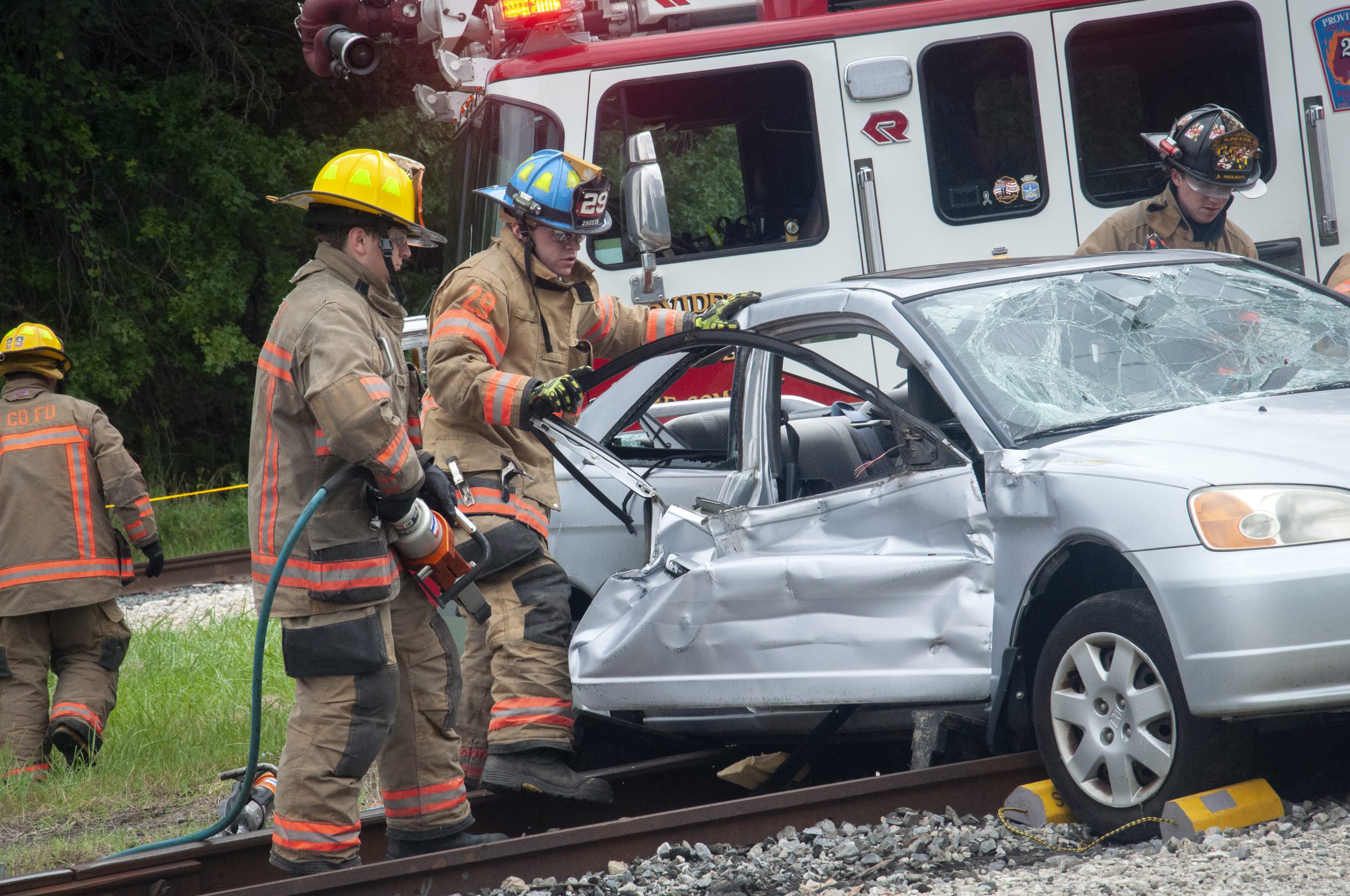 A group of first responders remove a crash test dummy from a car that has been in a collision.